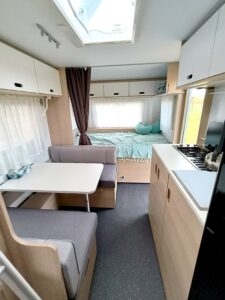 Wnętrze przyczepy Adria Aviva 522 PT – część dzienna z jadalnią, kuchenką i dużym łóżkiem małżeńskim