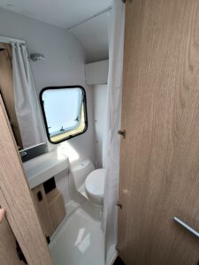 Wnętrze łazienki w przyczepie Aviva 522 PT z widoczną toaletą, umywalką i oknem